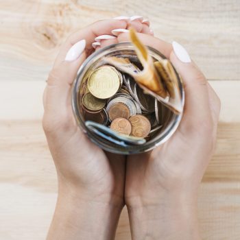 mano de mujer sosteniendo el ahorro en el tarro contra el fondo de madera